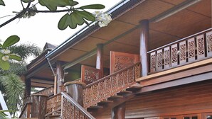 A wooden staircase with intricate carvings leading to a balcony with decorative railings.