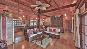 A spacious living room with wooden floors, a sofa set, a coffee table, and a ceiling fan.