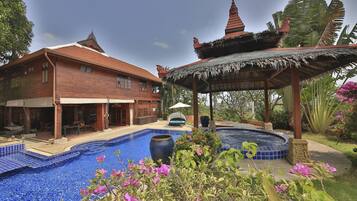 A large house with a swimming pool, a hot tub, and a gazebo.