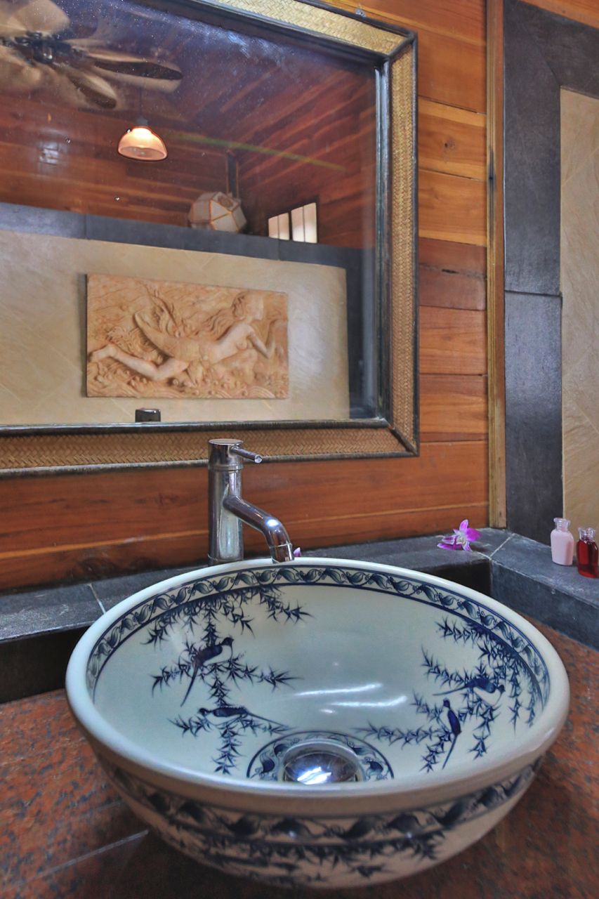 Ein Badezimmer mit einem großen Keramikbecken, einem gerahmten Kunstwerk an der Wand und einem Deckenventilator.