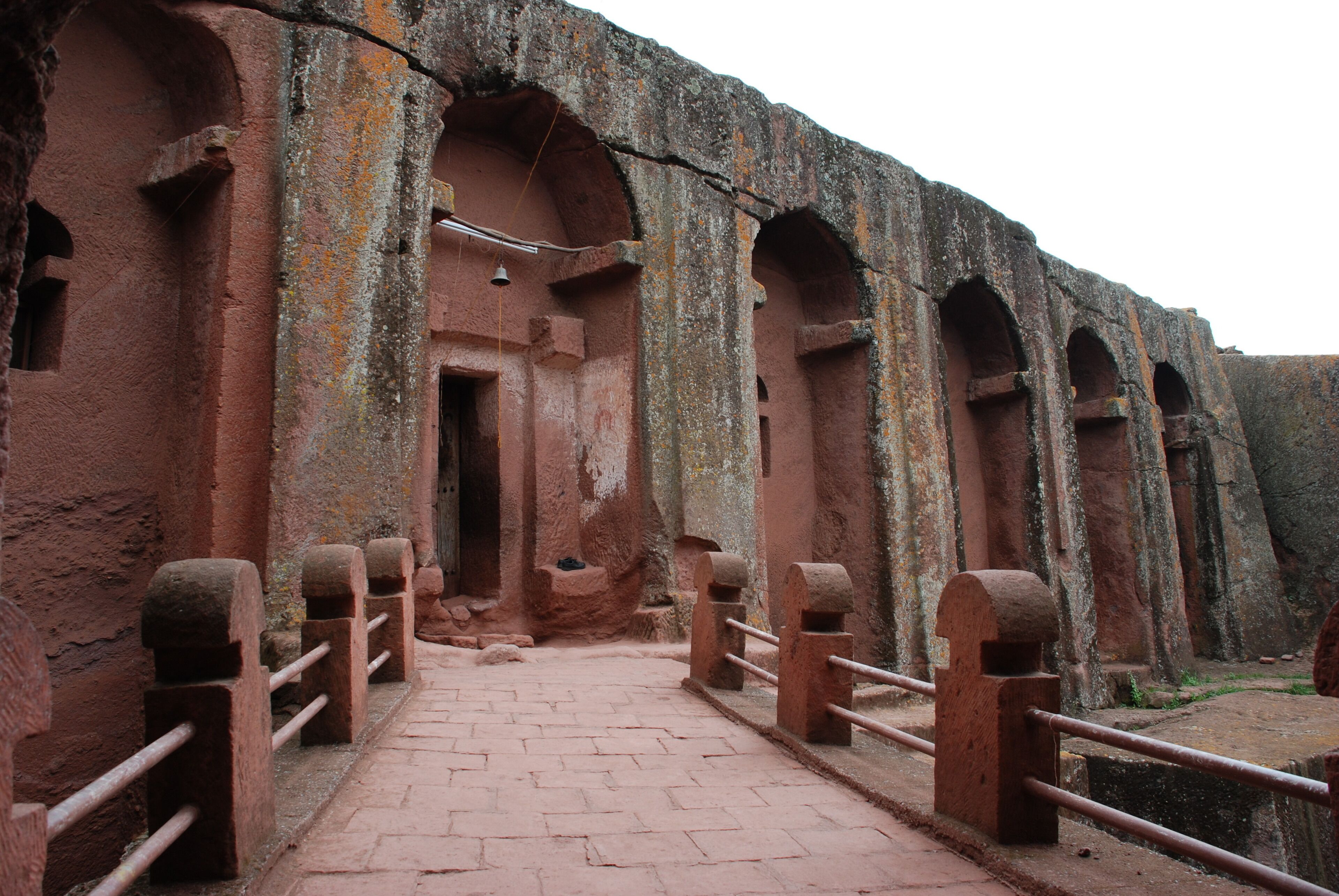 A pathway leading to a large, ancient structure with arched doorways and stone railings.