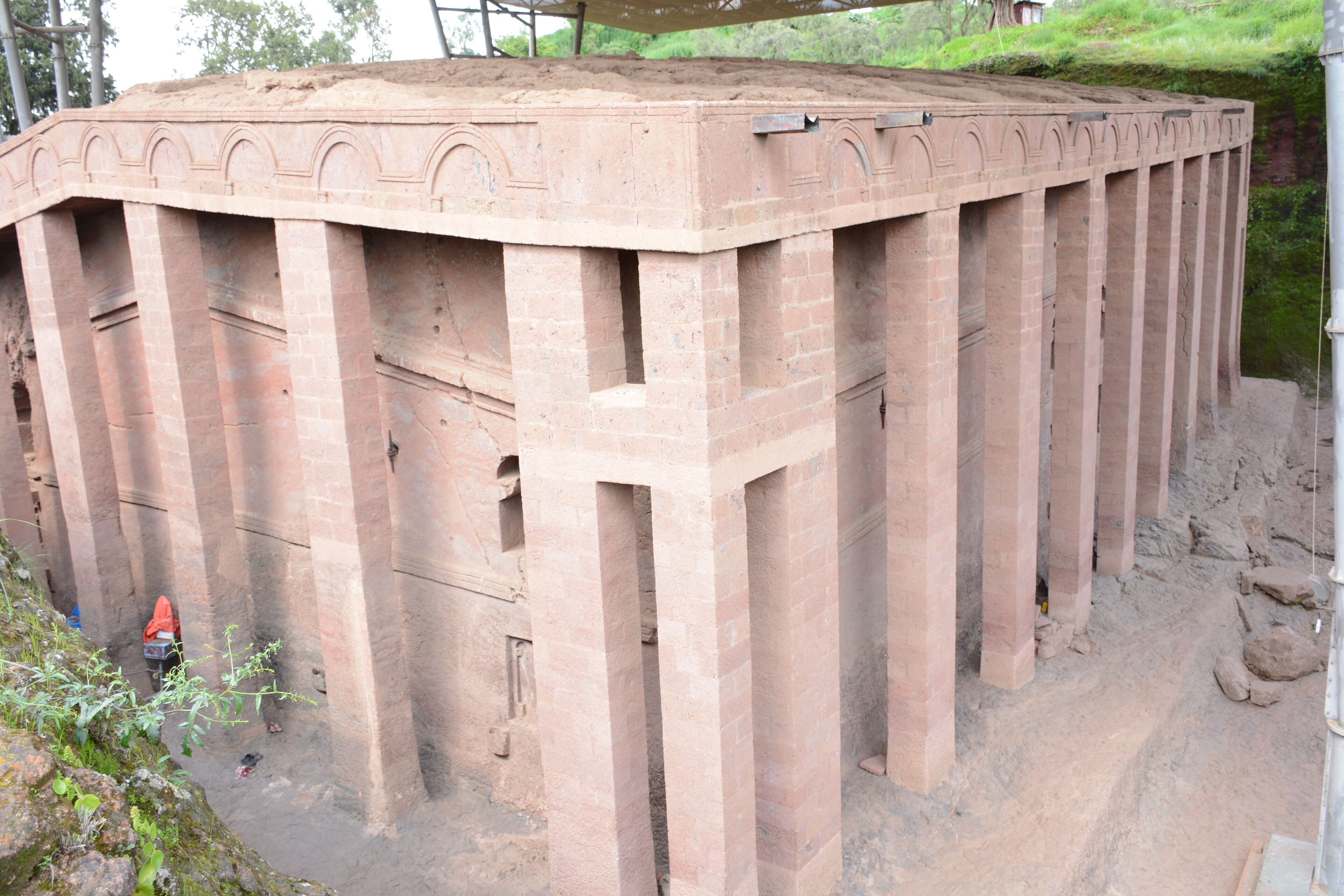 Une grande structure circulaire en briques, dotée d’un toit plat et de nombreuses colonnes.