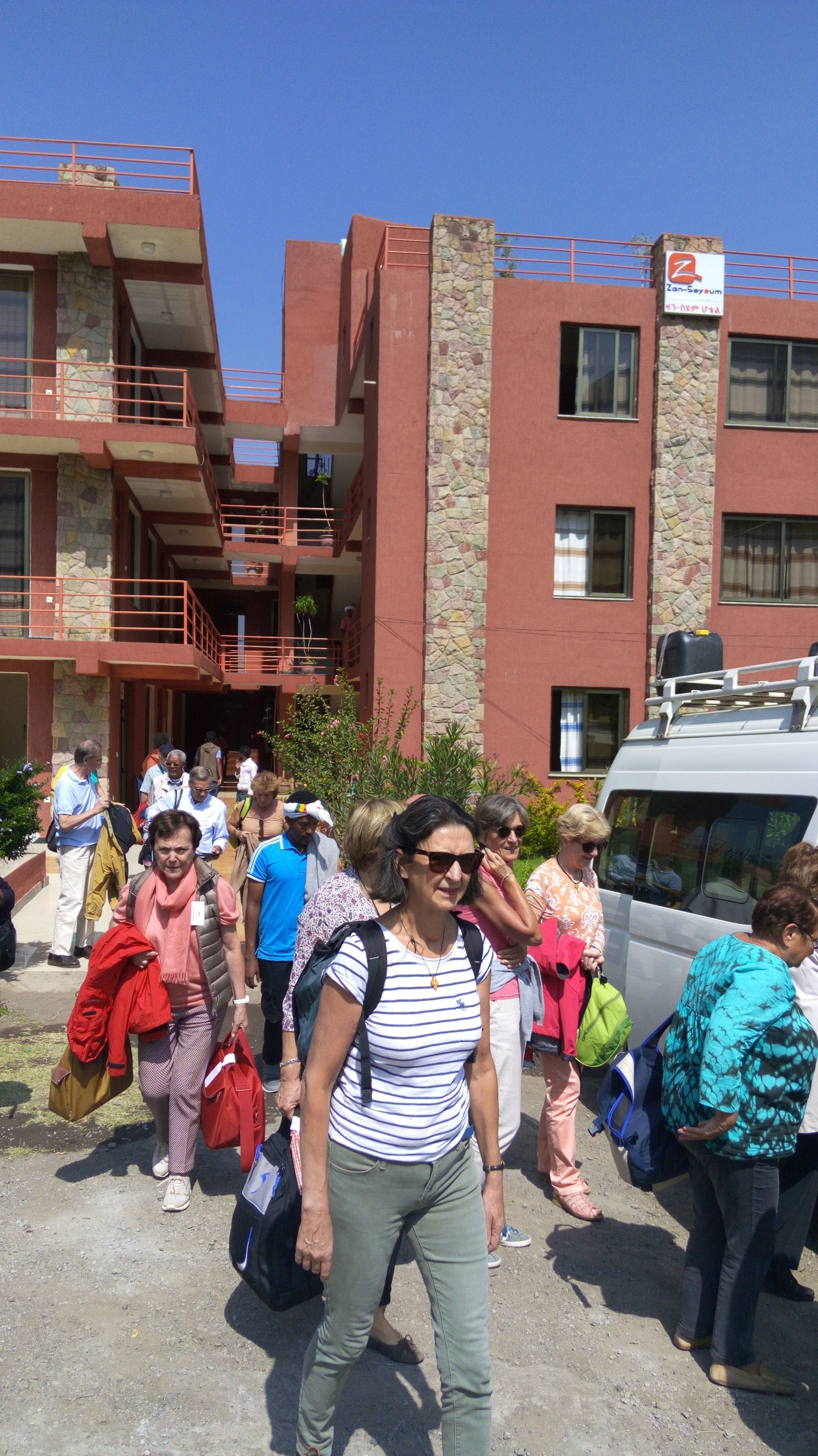 Un grupo de personas caminando hacia un edificio con fachada de piedra y varios balcones.