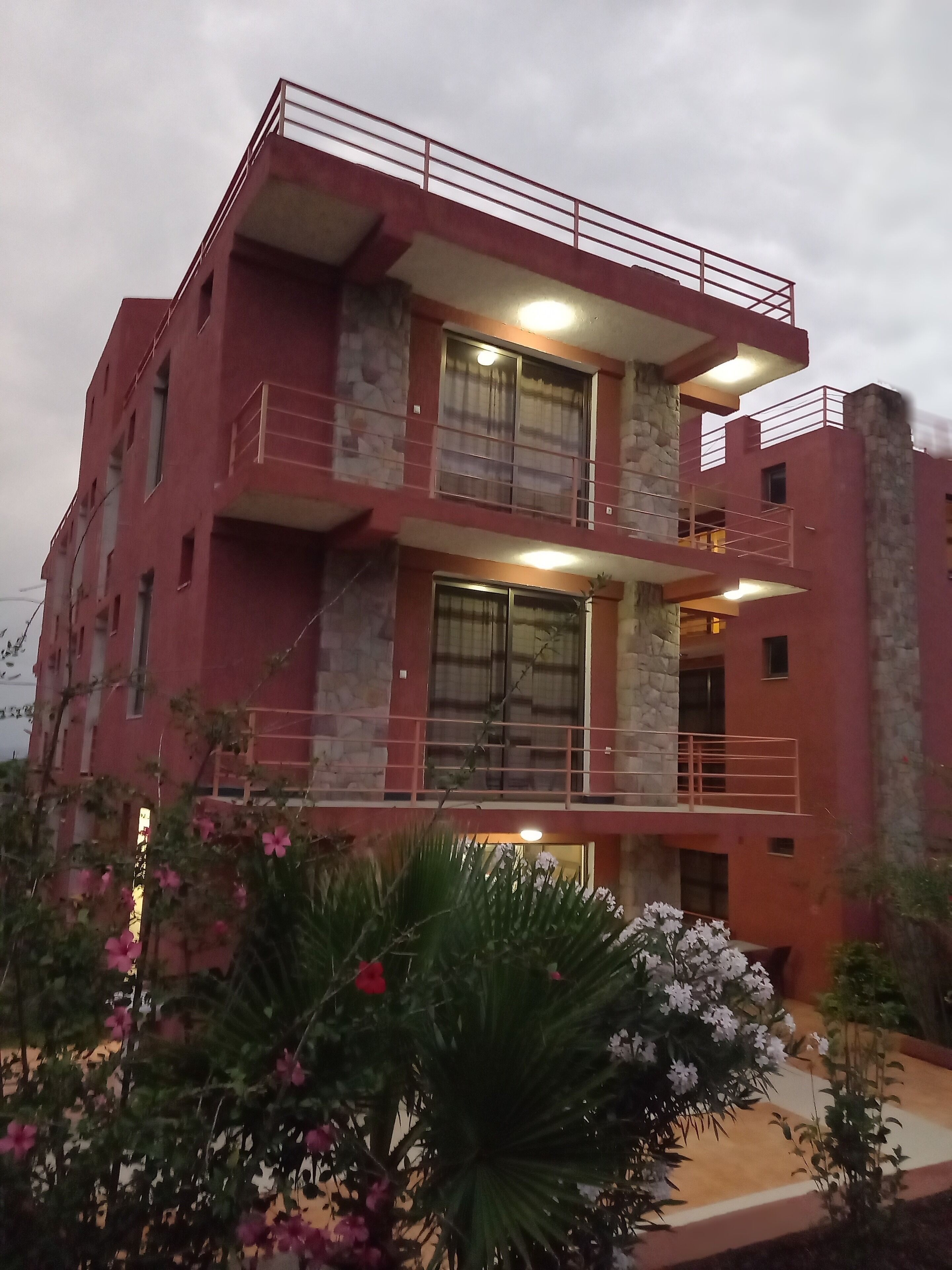 A multi-story building with balconies, large windows, and a stone facade.