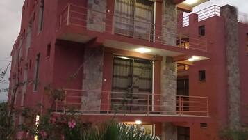 A multi-story building with balconies, large windows, and a stone facade.