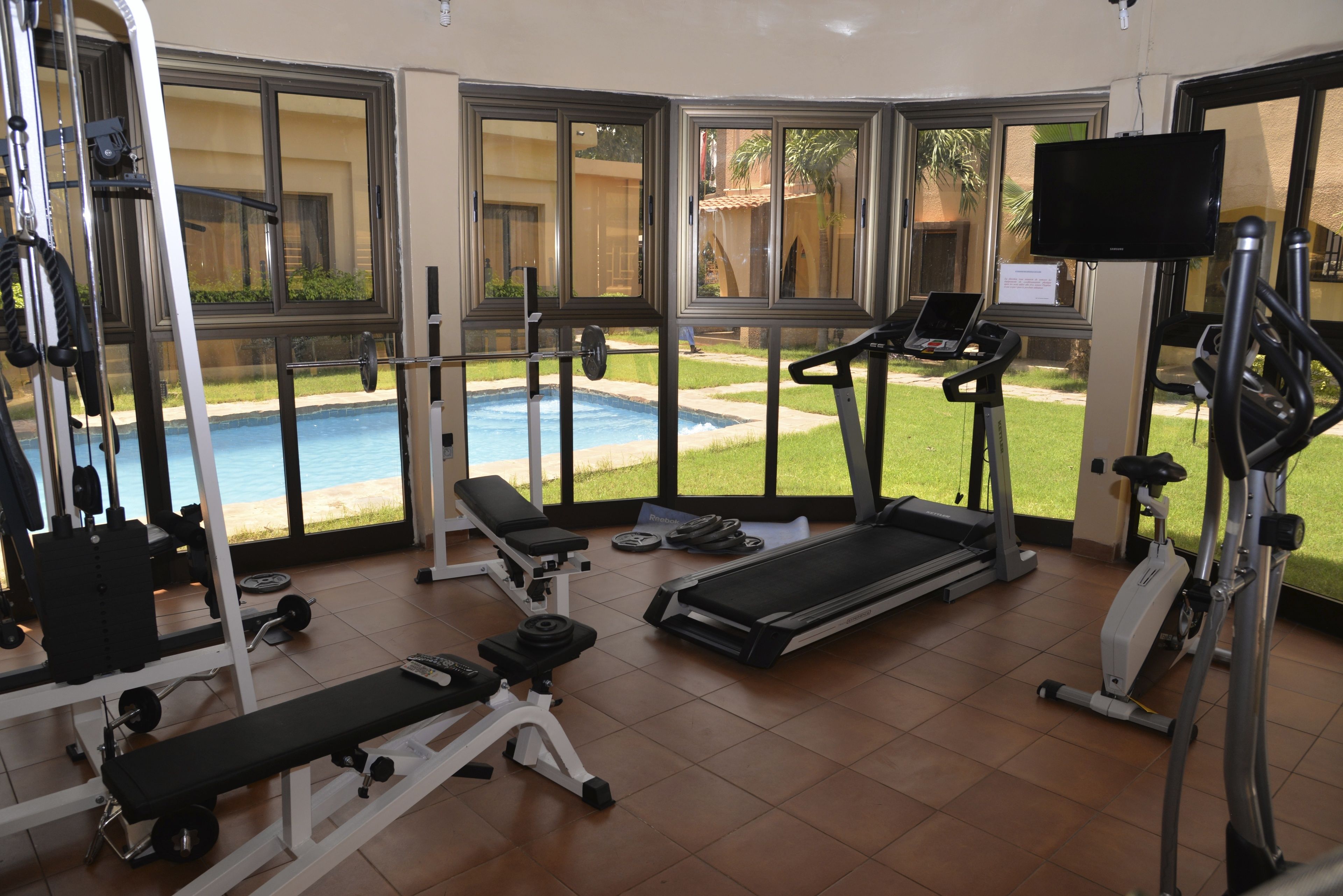 A gym with cardio machines, weight benches, and a pool view.