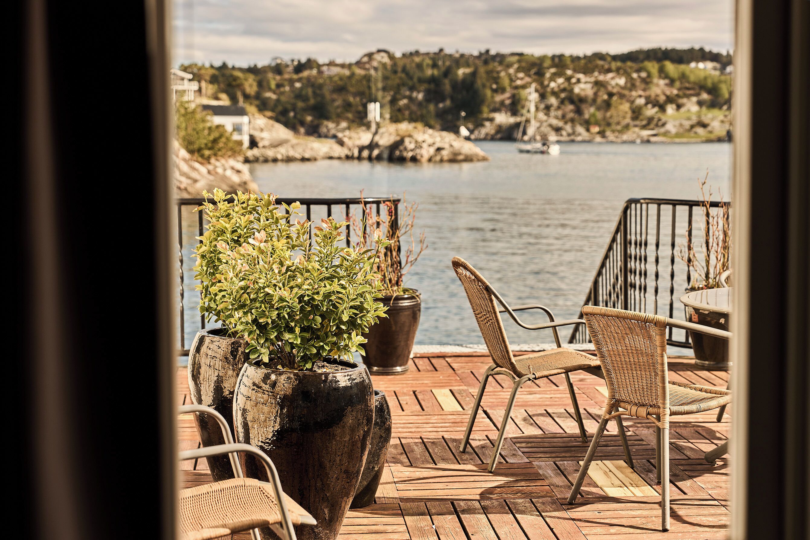A wooden deck with outdoor furniture overlooking a body of water.