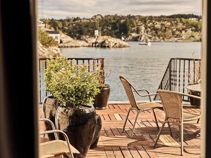 A wooden deck with outdoor furniture overlooking a body of water.