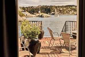 A wooden deck with outdoor furniture overlooking a body of water. - Bekkjarvik Gjestgiveri | Beckerwyc House (Austevoll)