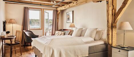 A bedroom with a bed, bedside tables, a chair, a desk, and a window with curtains.