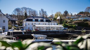 A waterfront property with a large building, docked boats, and a clear view of the water. - Bekkjarvik Gjestgiveri | Beckerwyc House (Austevoll)