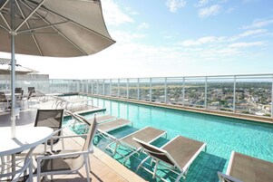 Una piscina al aire libre, sombrillas, sillones reclinables de piscina