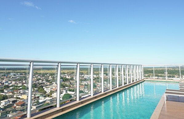 A pool with a glass barrier and a view of a residential area.