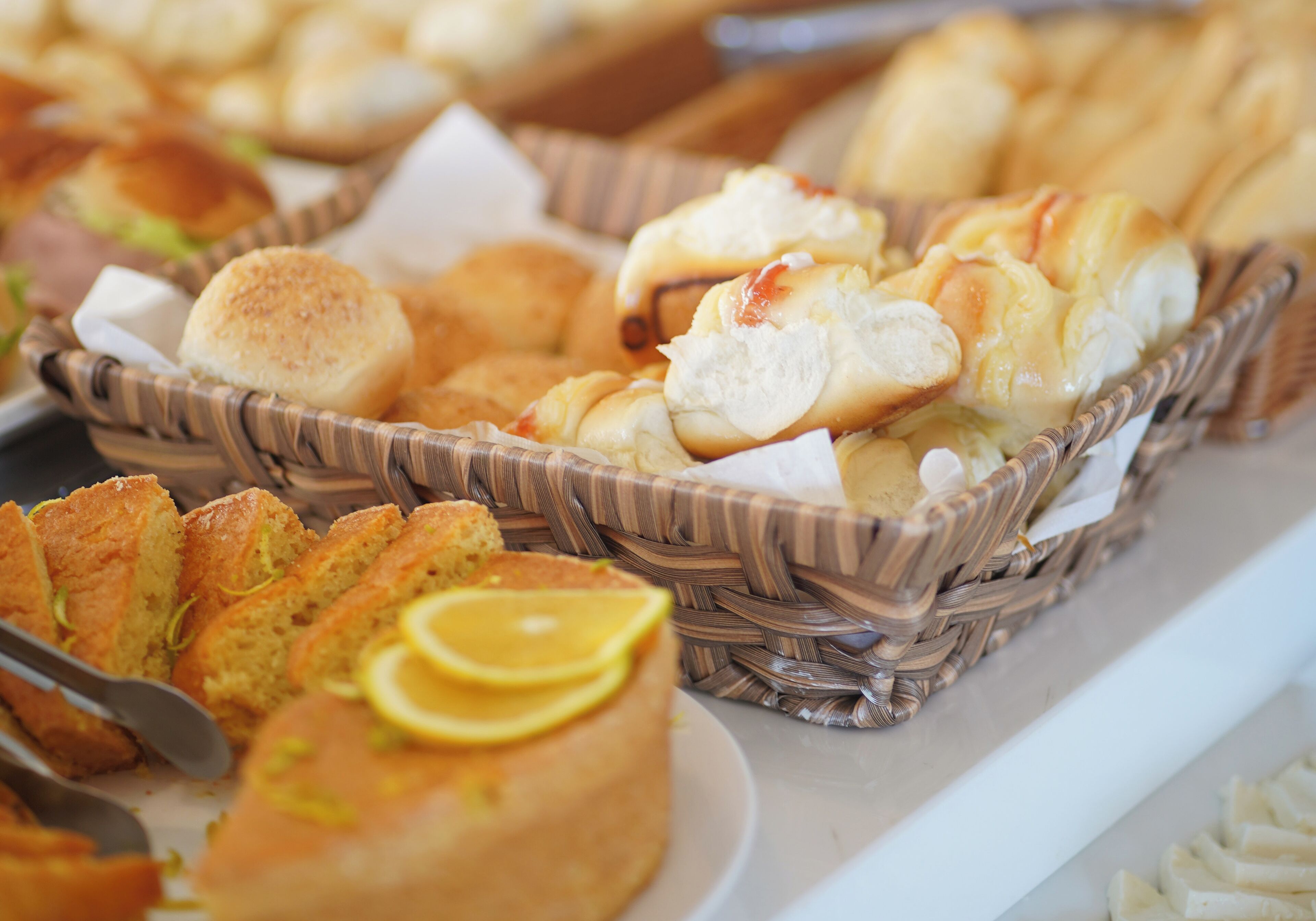 A buffet with various baked goods including bread rolls, muffins, and pastries in wicker baskets.