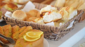 A buffet with various baked goods including bread rolls, muffins, and pastries in wicker baskets.