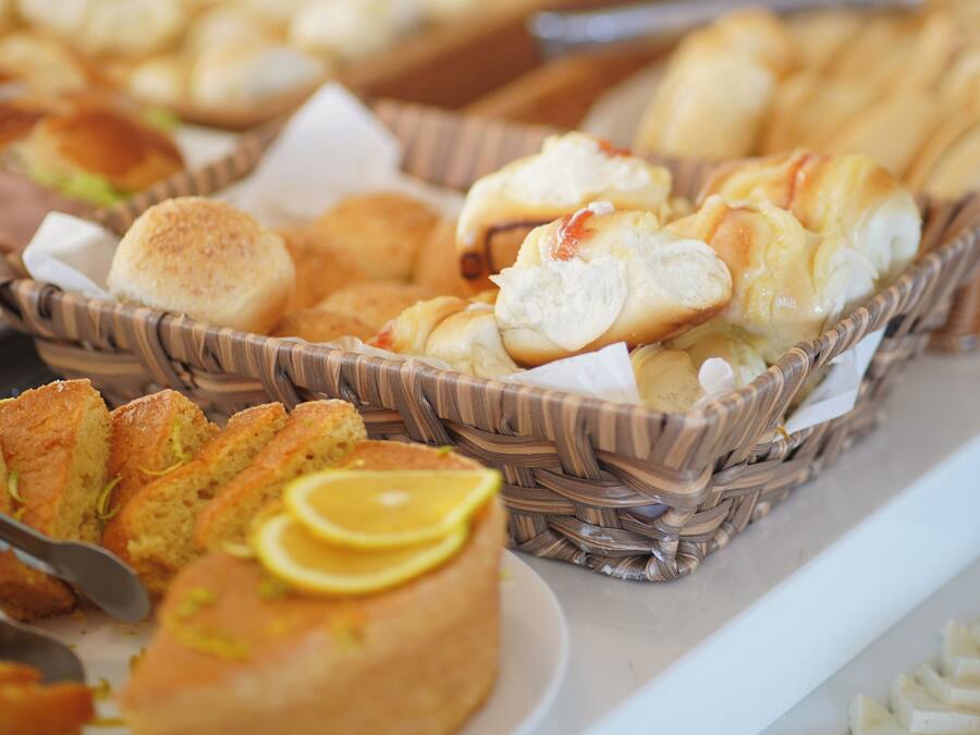A buffet with various baked goods including bread rolls, muffins, and pastries in wicker baskets.