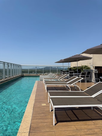 Una piscina al aire libre, sombrillas, sillones reclinables de piscina