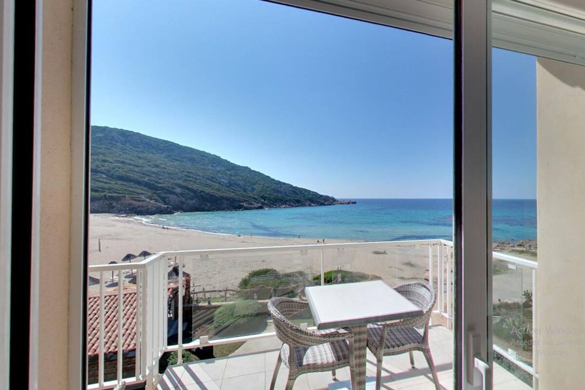 A balcony with a view of a beach and the sea.