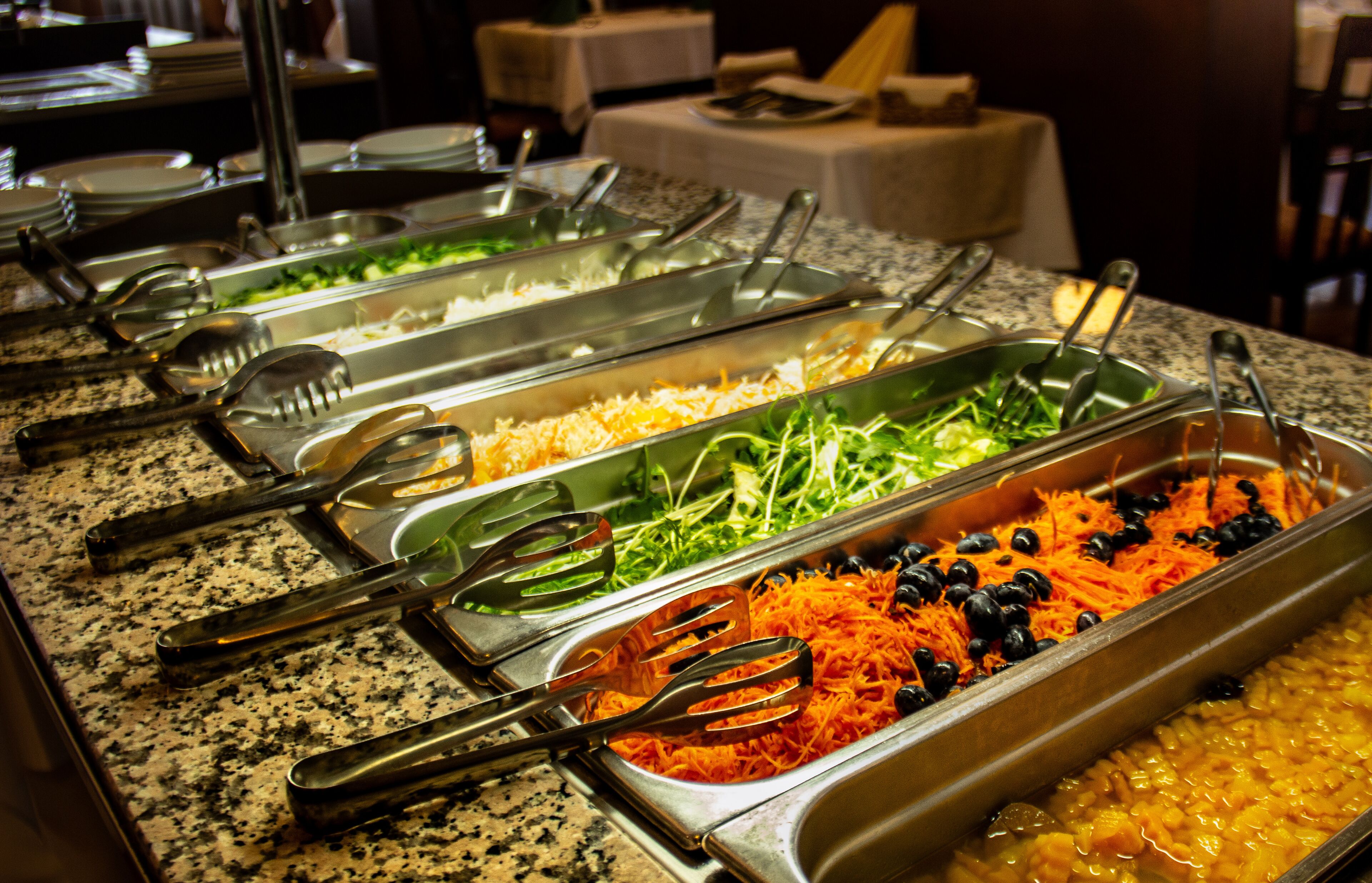 Buffet com diversas opções de comida e utensílios de servir.