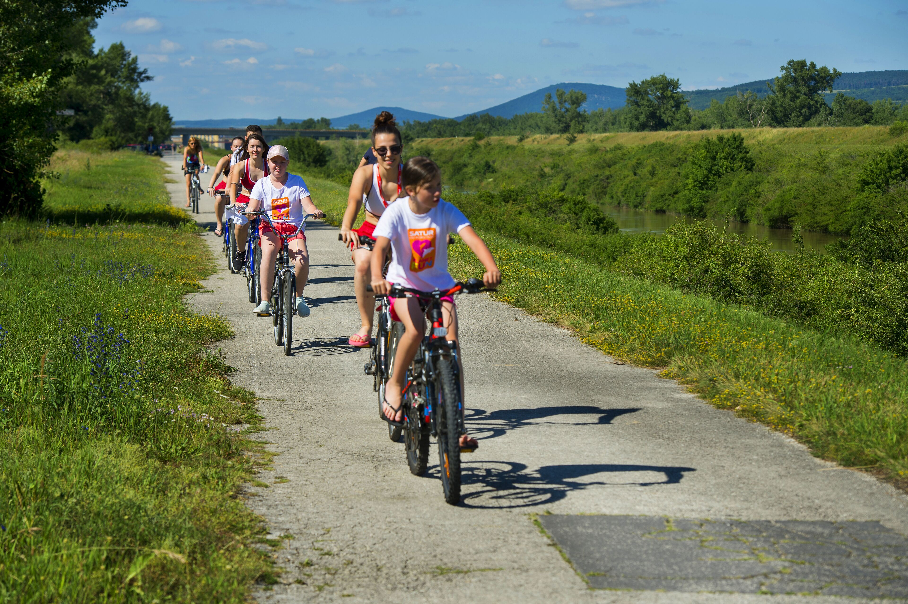 A group of people cycling on a paved path surrounded by greenery.