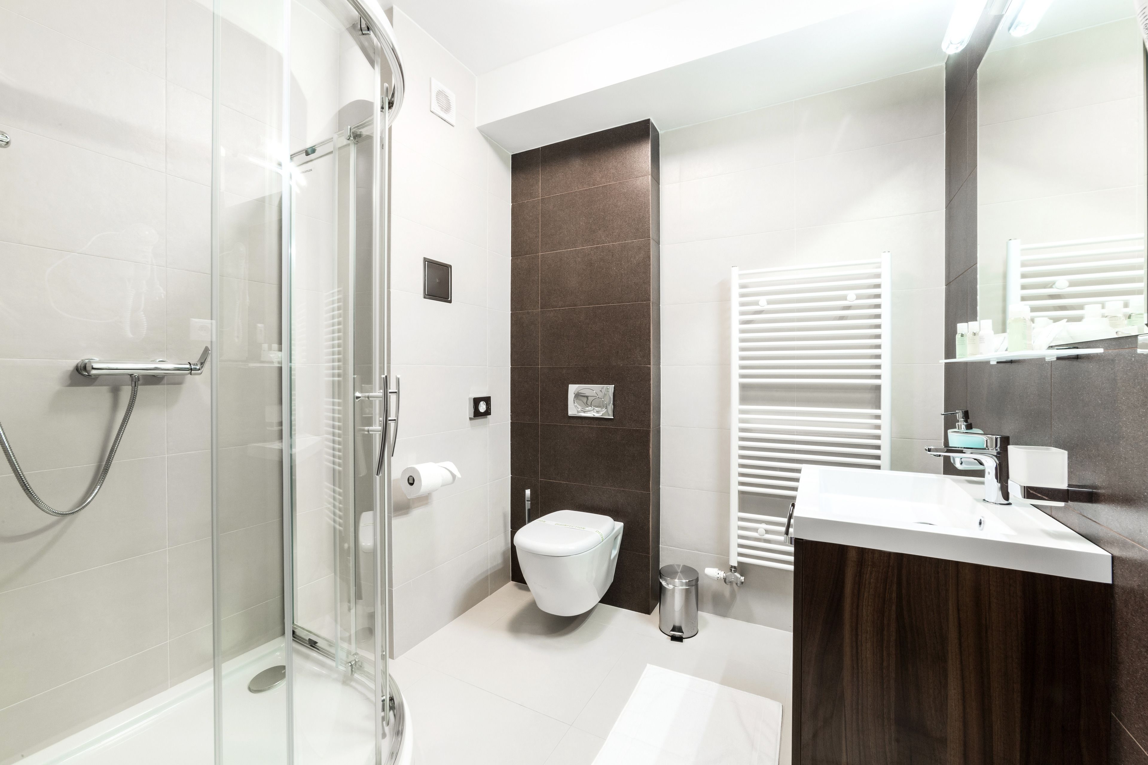 A modern bathroom with a glass shower enclosure, a white toilet, and a wooden vanity with a sink.