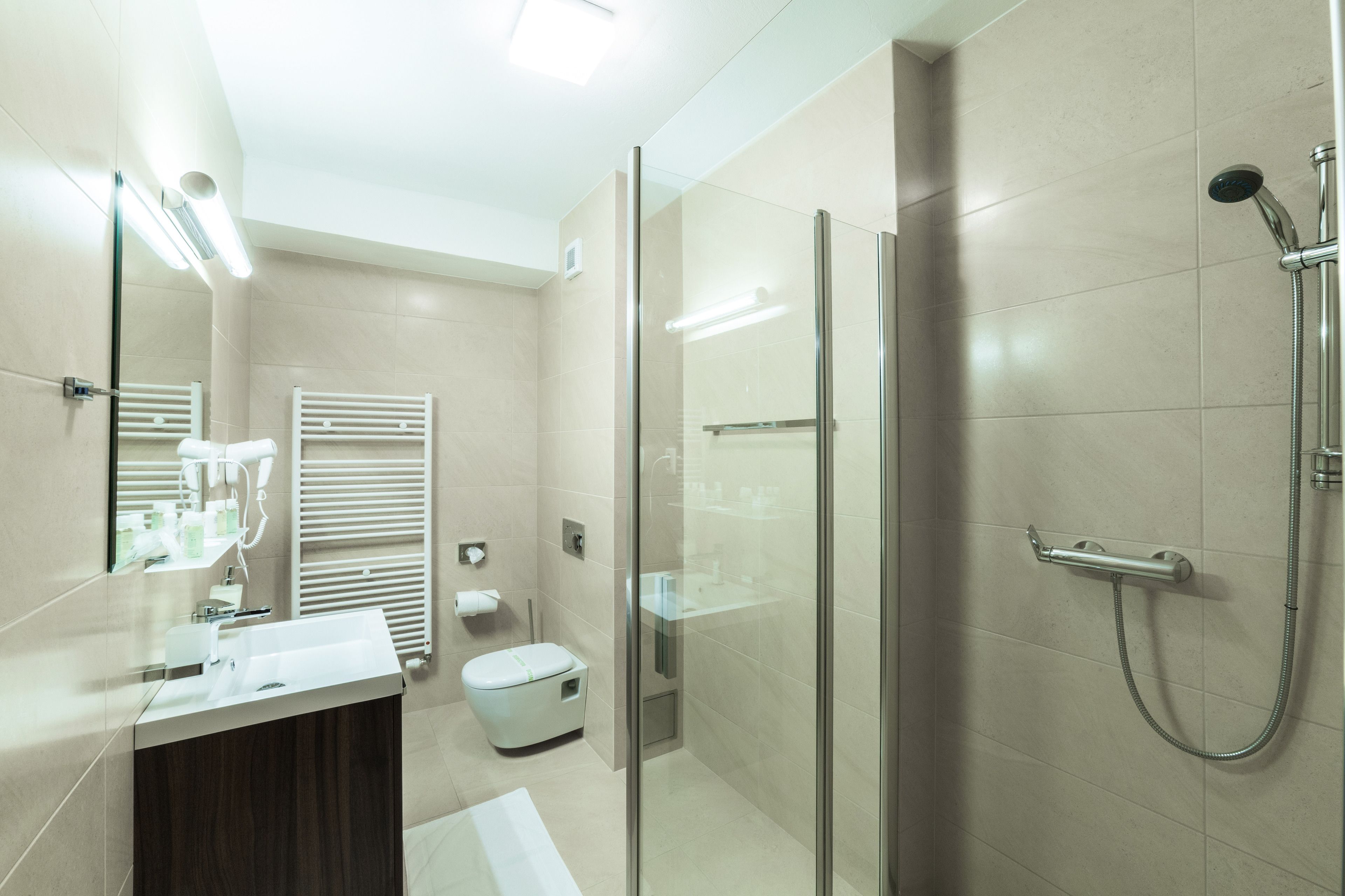 A modern bathroom with a glass shower enclosure, a vanity with a mirror, and a toilet.