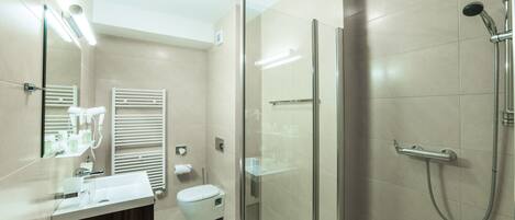 A modern bathroom with a glass shower enclosure, a vanity with a mirror, and a toilet.