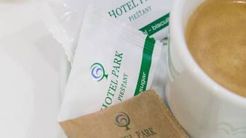 A breakfast setting with a cup of coffee, a glass of milk, and two packets of sugar labeled 'Hotel Park'.