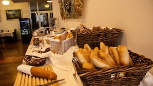 A buffet table with various breads and pastries, a knife, and a basket. - Hotel Park (Piestany)