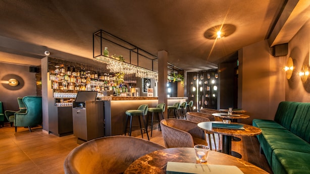 A bar area with a marble countertop, bar stools, and a green upholstered sofa. - Hotel Park (Piestany)