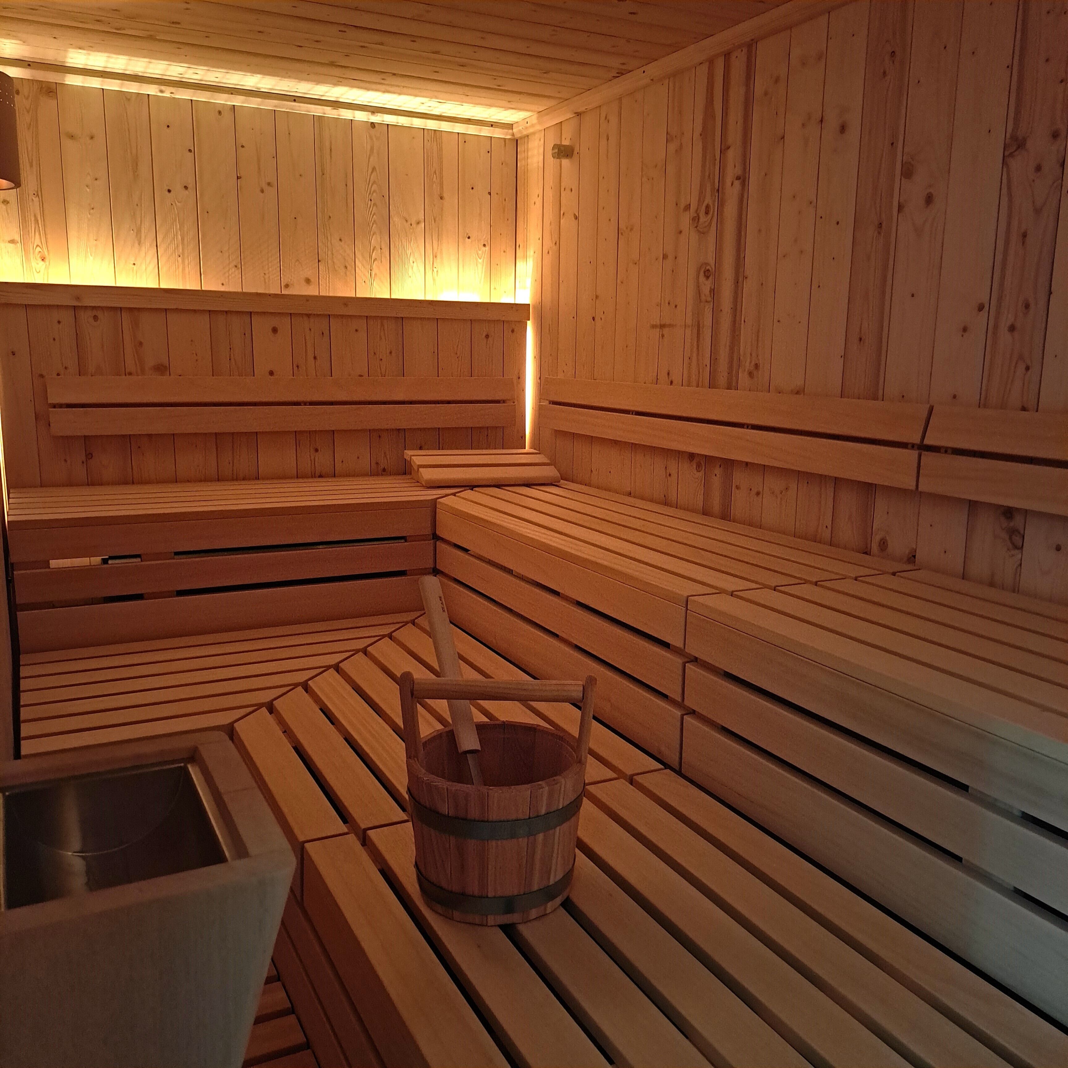 Una sauna con bancos de madera y un cubo de madera.