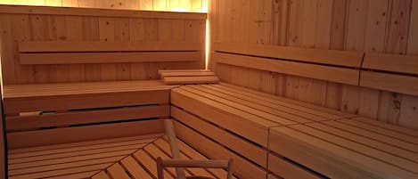 Una sauna con bancos de madera y un cubo de madera.