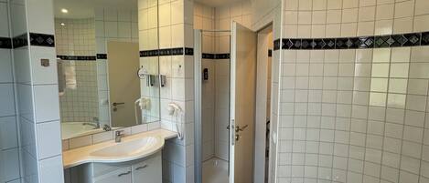 Un baño moderno con una bañera grande, un lavamanos doble, una ducha con mampara de vidrio y un espejo con detalles de cerámica blanco y negro.