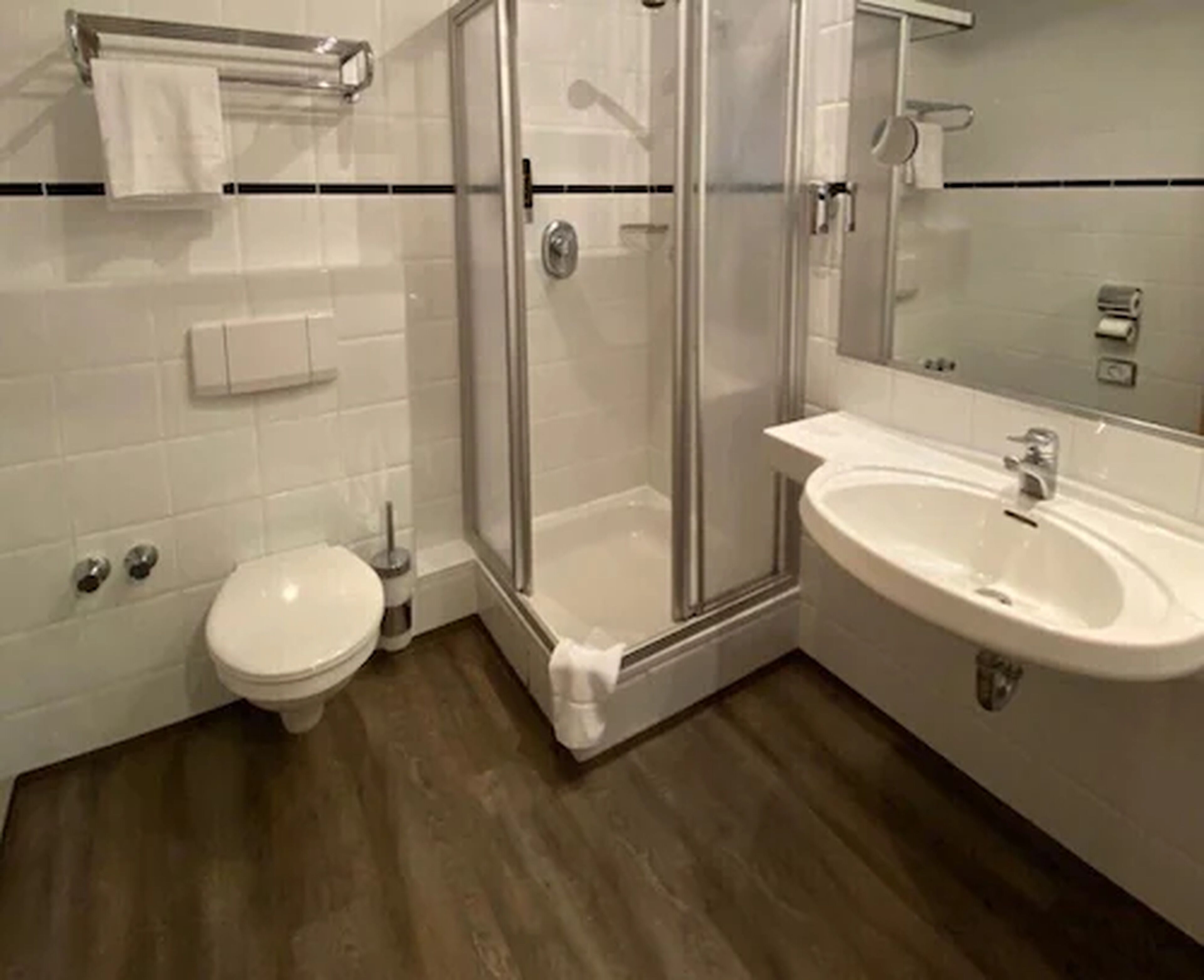 Un baño moderno con inodoro, ducha con mampara de vidrio y lavamanos.