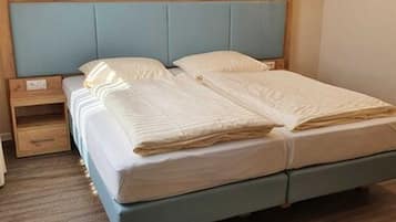 Un dormitorio con cama, cabecera de madera, mesita de noche y un cajón pequeño.