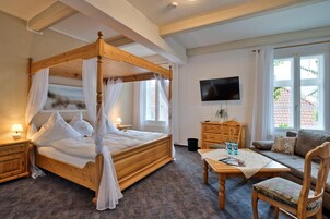 Un dormitorio con cama con dosel, televisor, sofá y mesa de comedor.