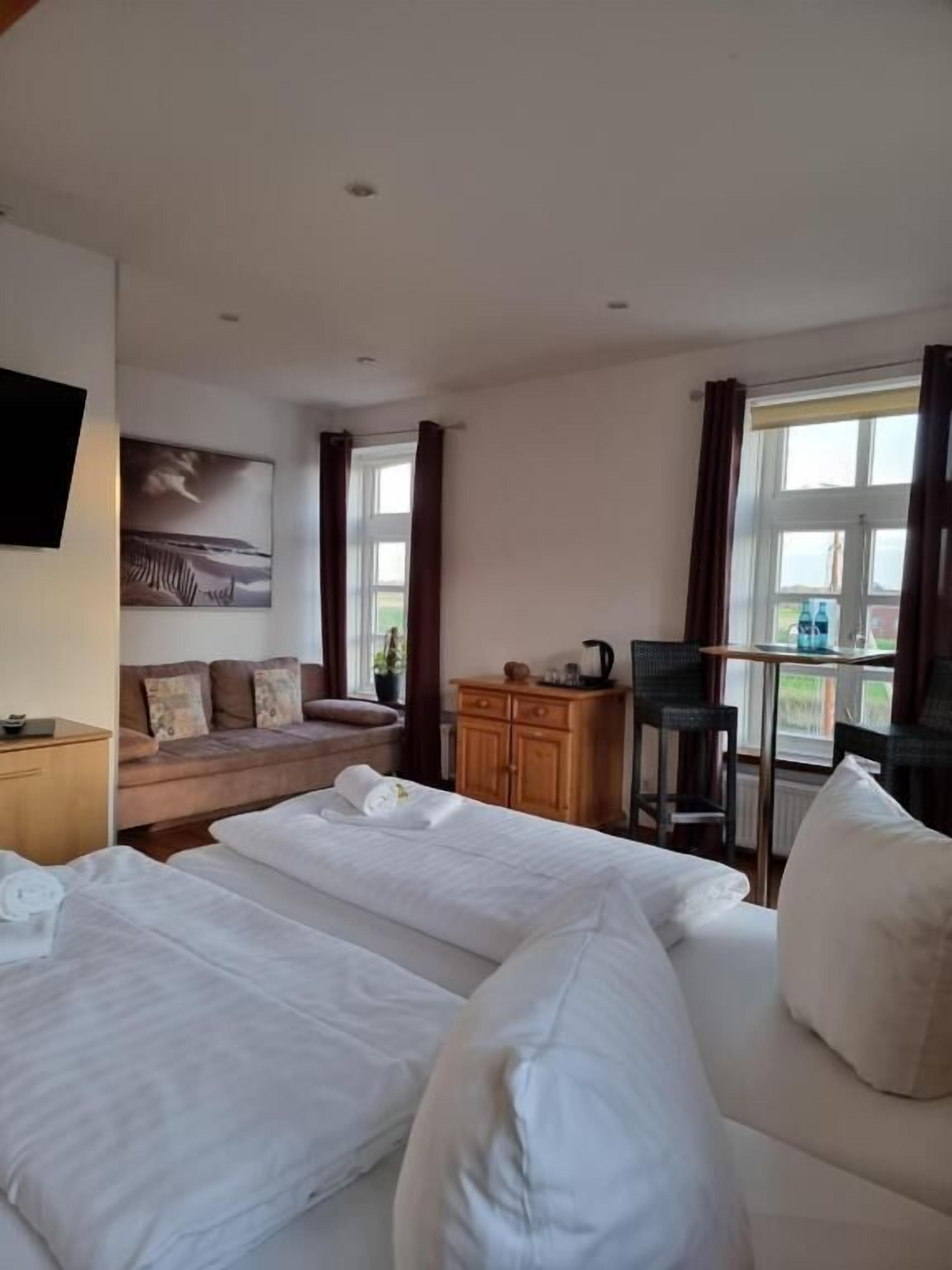 Een hotelkamer met twee bedden, een bank, een bureau en een raam met gordijnen.
