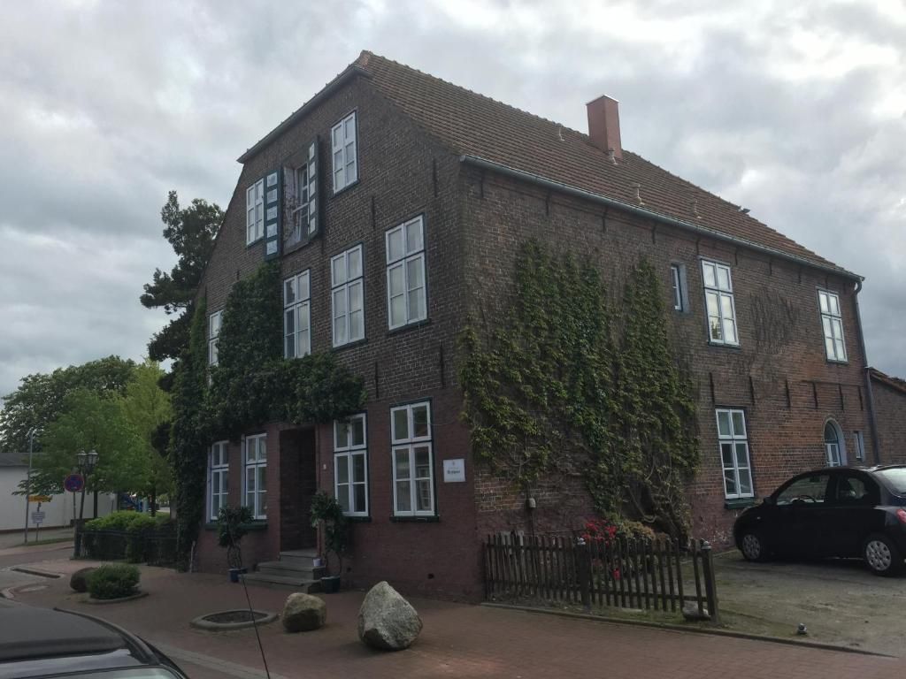 A two-story brick building with a flat roof, large windows, and a paved driveway.