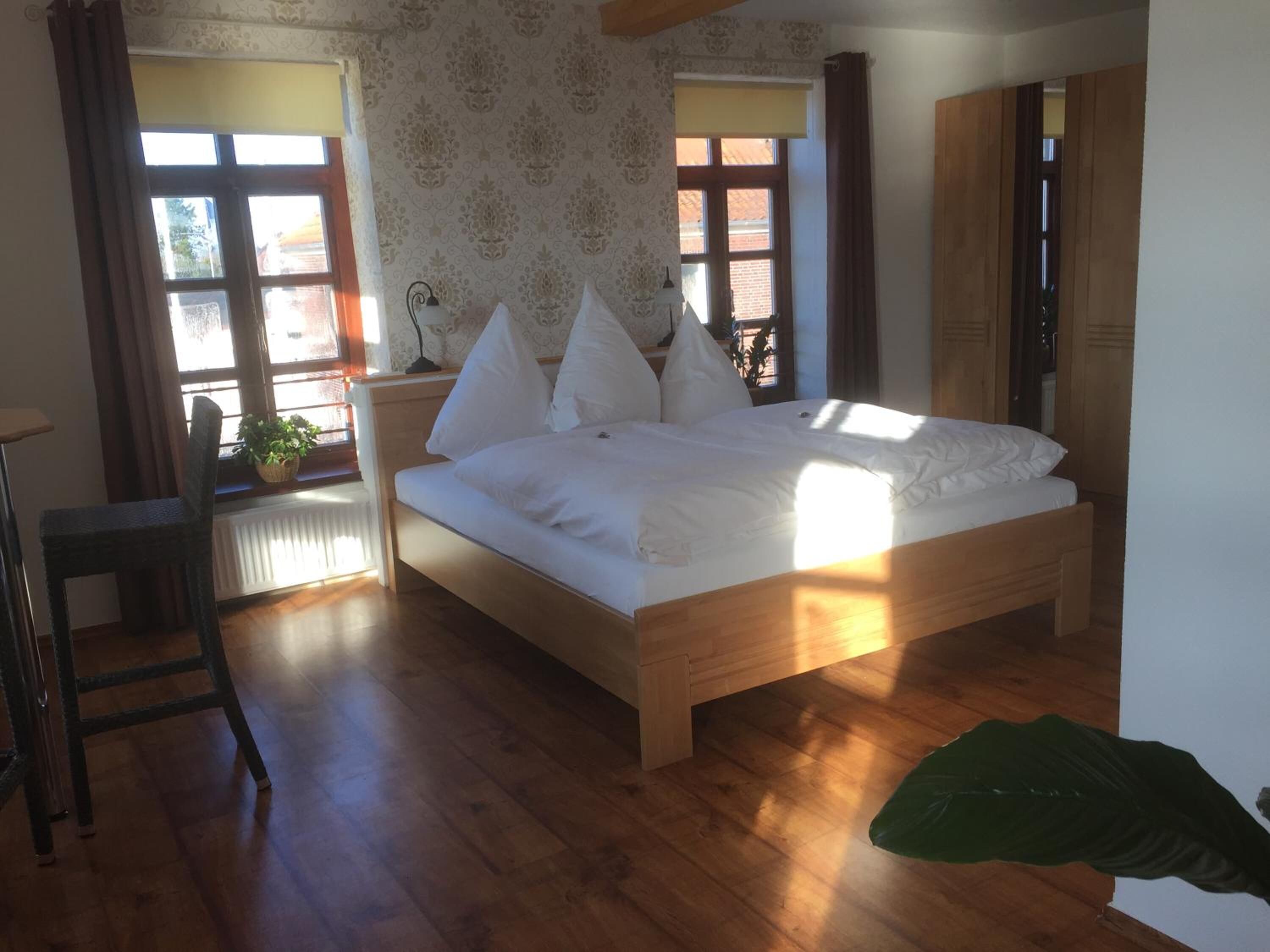 A bedroom with a wooden bed, a radiator, a chair, and a large plant.