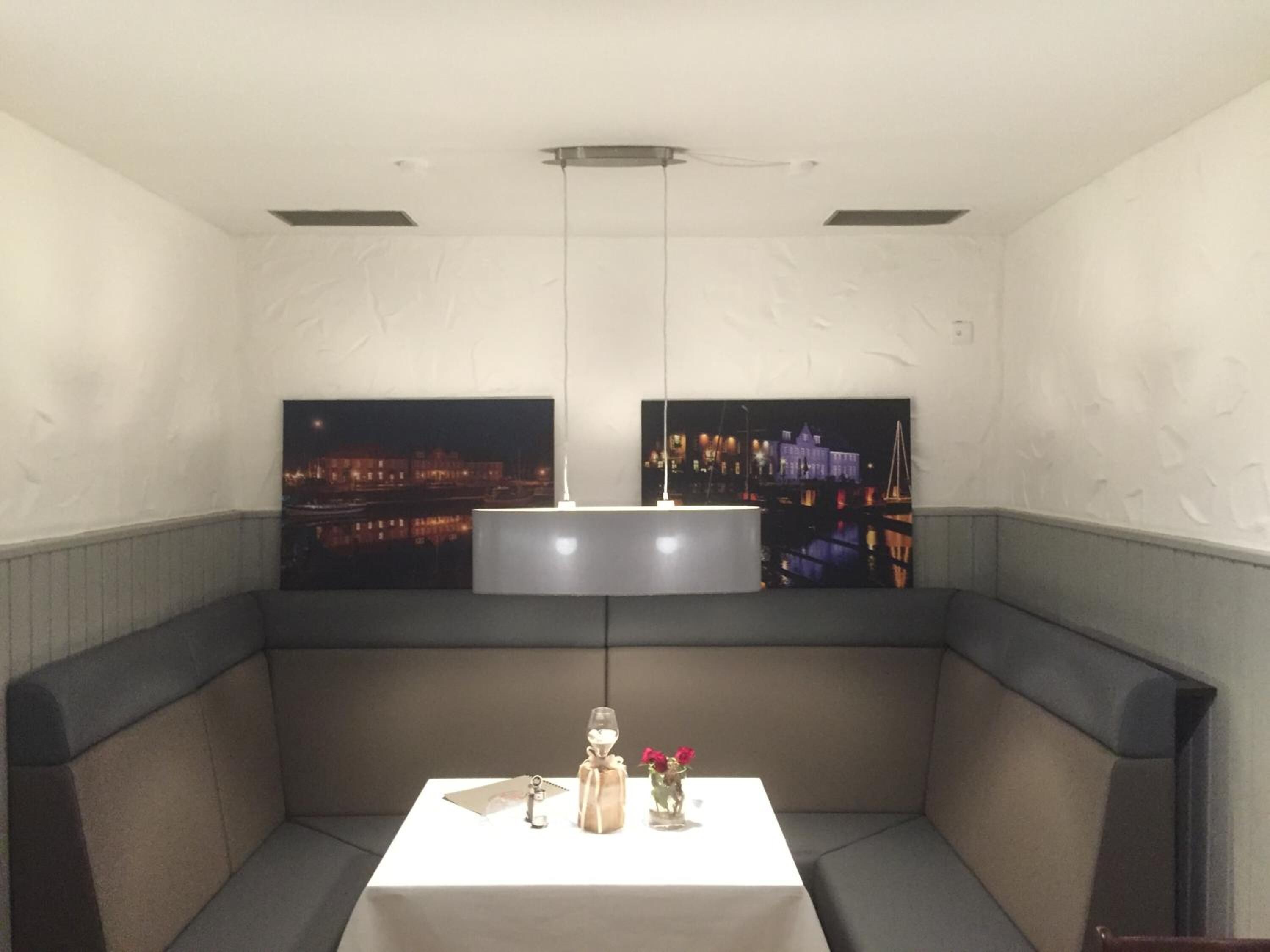 Un'area pranzo con sedute a bancada, un tavolo con un vaso di fiori e due fotografie incorniciate di panorami urbani alle pareti.
