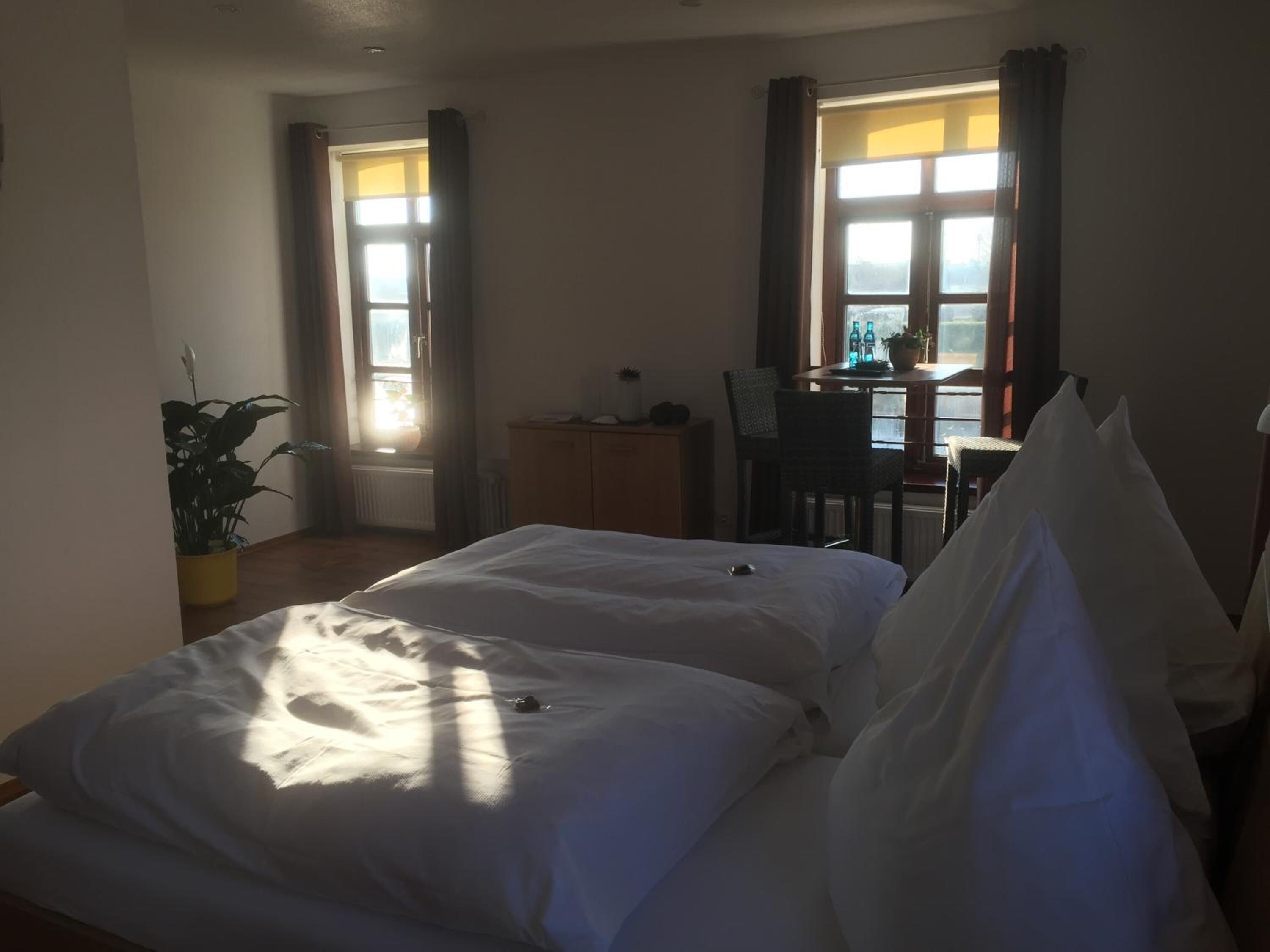 A hotel room with two beds, a desk, and a chair near a window.