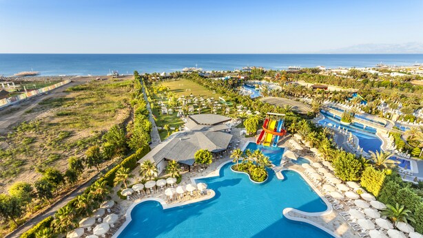Ein Resort mit einem großen Schwimmbad, mehreren Liegebereichen und Blick auf den Ozean.