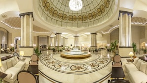 Eine großzügige Lobby mit einer zentralen Fontäne, Marmorböden und klassischen Säulen.