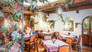 Un restaurante con mesas y sillas de madera, decoración de hiedra y un muro de ladrillo.