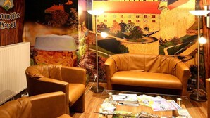 Una habitación con un amplio mural de un castillo, sillones de cuero, una mesa de centro de vidrio y una lámpara de pie.