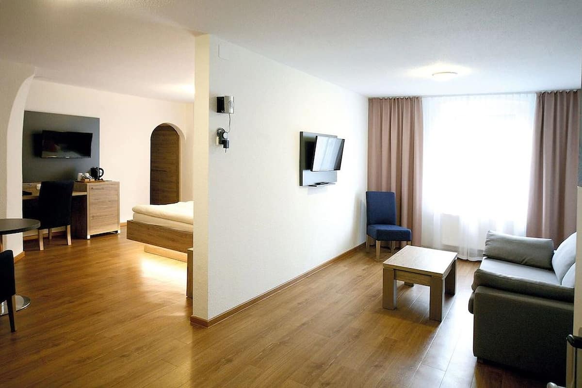 Ein modernes Wohnzimmer mit Sofa, Couchtisch, Fernseher und einem Essbereich mit Tisch und Stühlen.