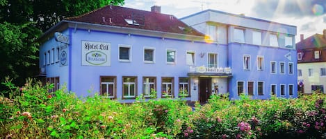 Un edificio de hotel con un letrero que dice "Hotel Ell". Presenta un estilo arquitectónico tradicional con múltiples ventanas y un balcón.