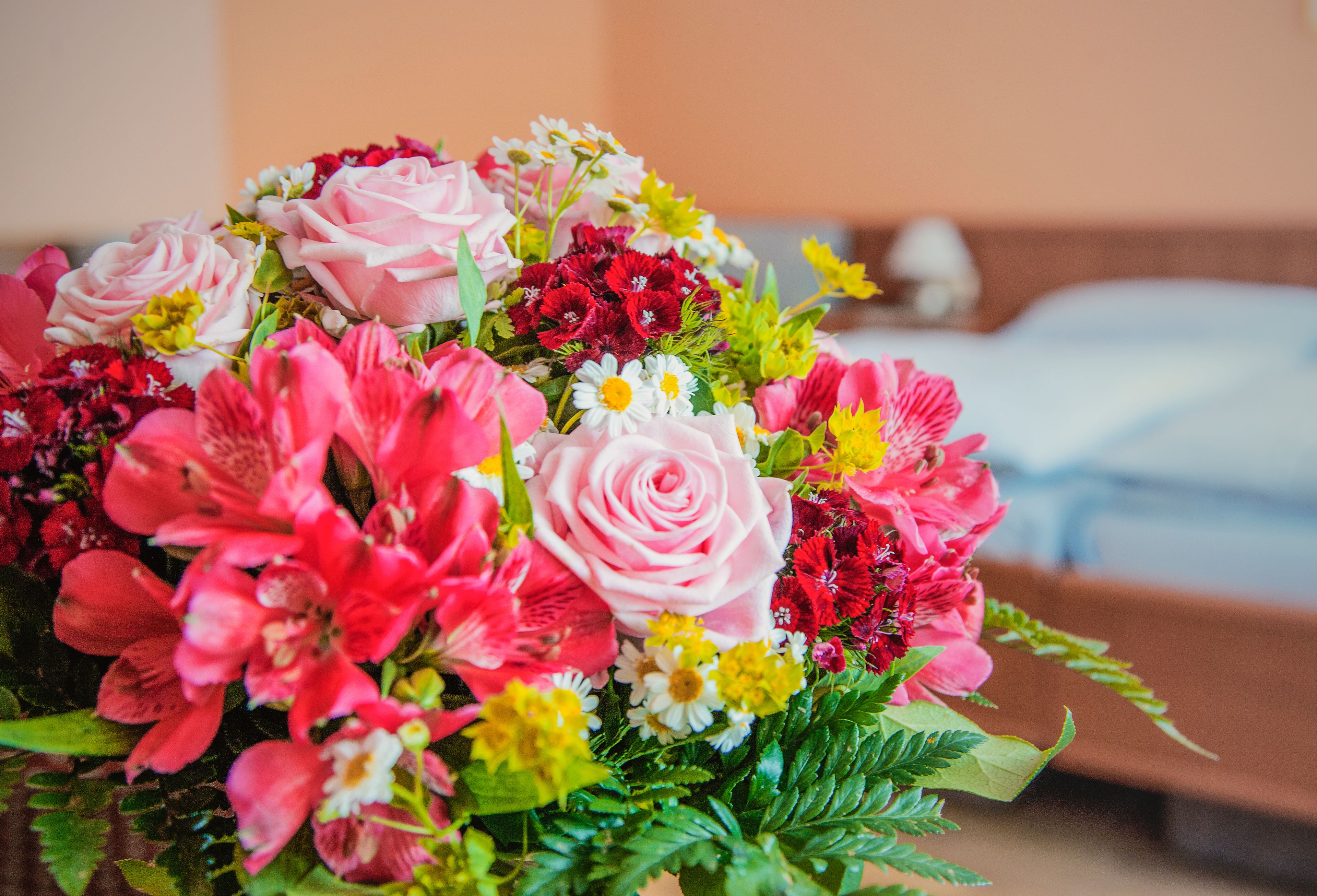 Ein Blumenstrauß mit verschiedenen Farben und Sorten, darunter Rosen und Lilien, auf einer Oberfläche platziert.