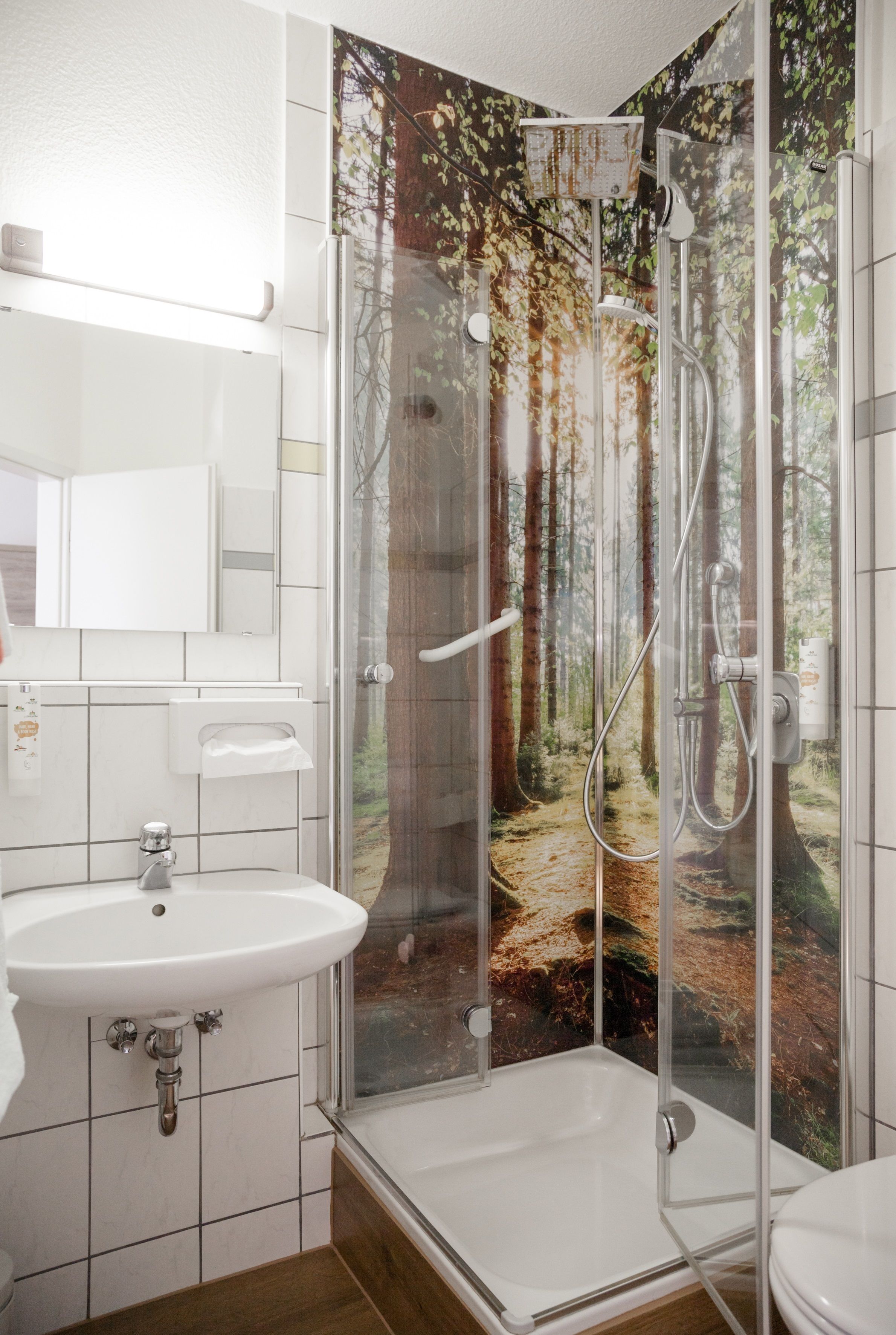 A bathroom with a glass-enclosed shower, a sink, and a toilet.