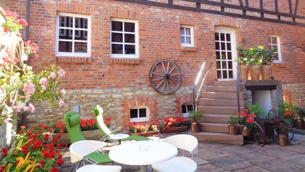 A Tudor-style building with a brick facade, multiple windows, and a stone archway. - Apartment Puell (Ingersleben)